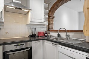 Cozinha com armários brancos, coifa de aço inoxidável, lava-louças Bosch e torradeira vermelha.
