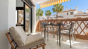 Un balcon avec un canapé, des chaises et une table.