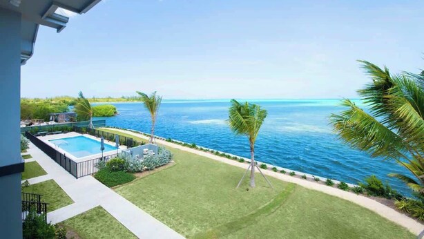 A pool with a view of the ocean, surrounded by palm trees and a well-maintained lawn. - Oceanfront 3BR + Private Dock at Sea Haven – Cassava Point Villa 4D (Patricks Island)