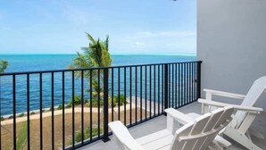 A balcony with a view of the ocean, white chairs, and a palm tree. - Oceanfront 3BR + Private Dock at Sea Haven – Cassava Point Villa 4D (Patricks Island)