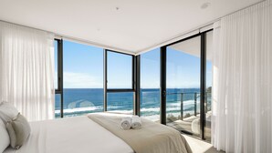 A bedroom with a large bed, white linens, and a view of the ocean through floor-to-ceiling windows. - Sandbar Burleigh Heads -Burleigh Letting (Burleigh Heads)