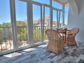 A balcony with large windows, wicker chairs, and a small table with a bowl and glass. - 18 Monte B, Miraflores, 2 pools (La Cala de Mijas)