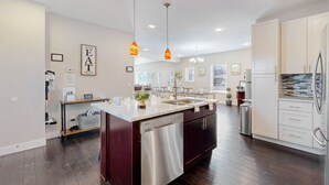Una cocina moderna con una isla central, electrodomésticos de acero inoxidable e iluminación colgante.