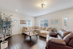 A living room with a sectional sofa, a coffee table, a leather armchair, and a potted plant.