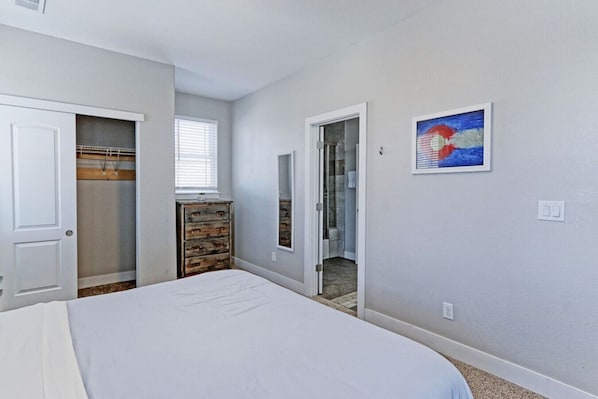A bedroom with a bed, a dresser, a closet, and a bathroom door.