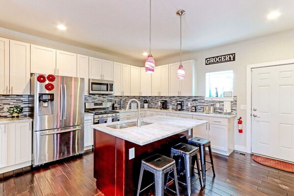 A modern kitchen with stainless steel appliances, a central island, and a 'GROCERY' sign on the wall.