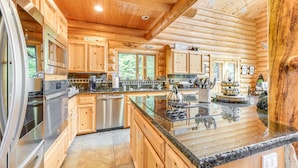 Eine Küchenzeile im Chalet-Stil mit Holdekor, Edelstahlgeräten und einer Arbeitsplatte aus Granit.