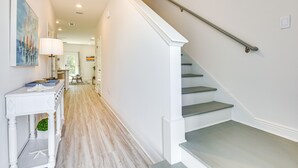 Una escalera con barandilla metálica, una consola decorada con objetos ornamentales, y un cuadro en la pared.