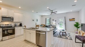 Una cocina moderna con armarios blancos, electrodomésticos de acero inoxidable y encimera de granito.