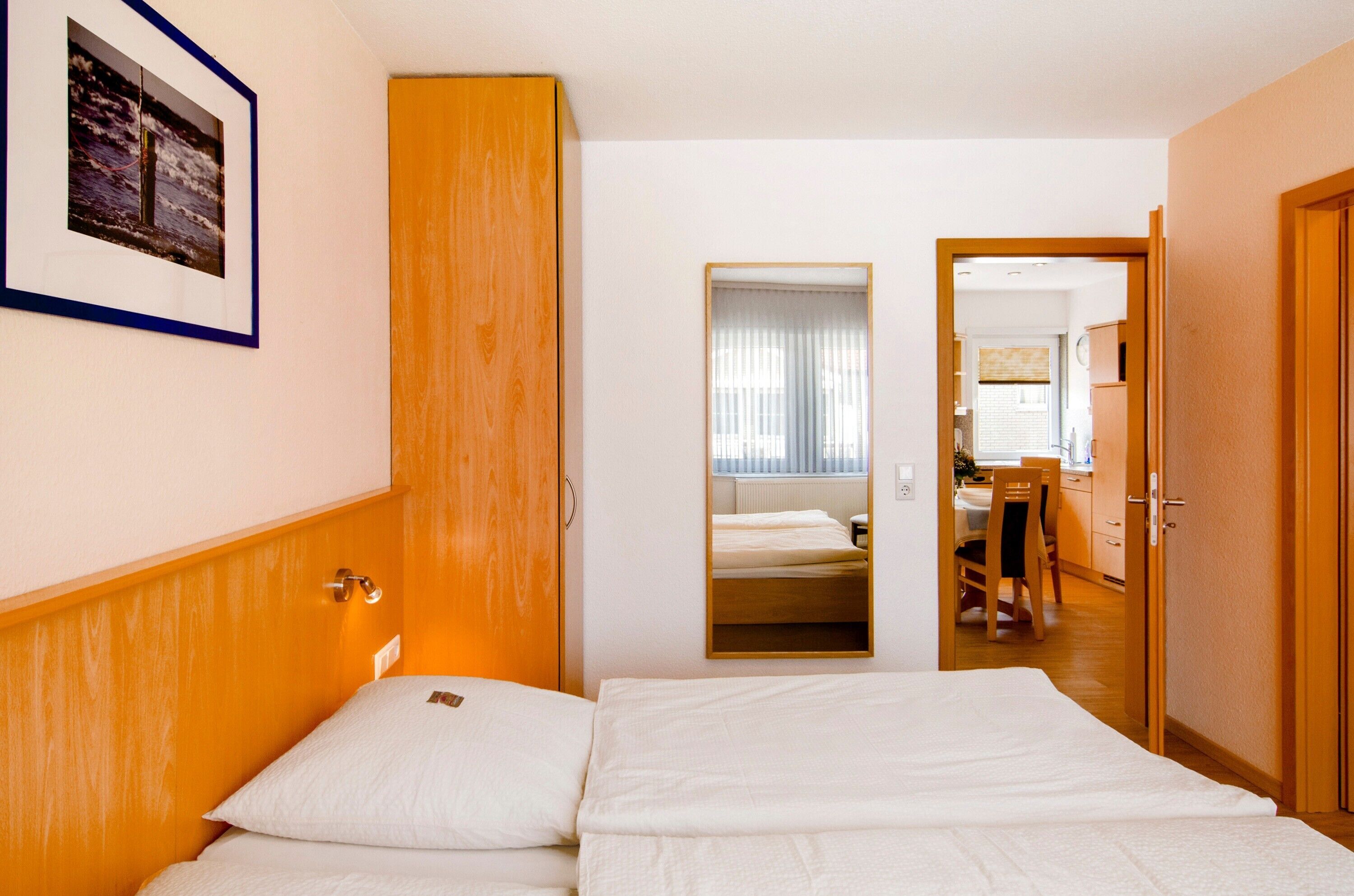 Ein Hotelzimmer mit einem Bett, einem Kleiderschrank, einem Spiegel und Blick in den Küchenbereich.