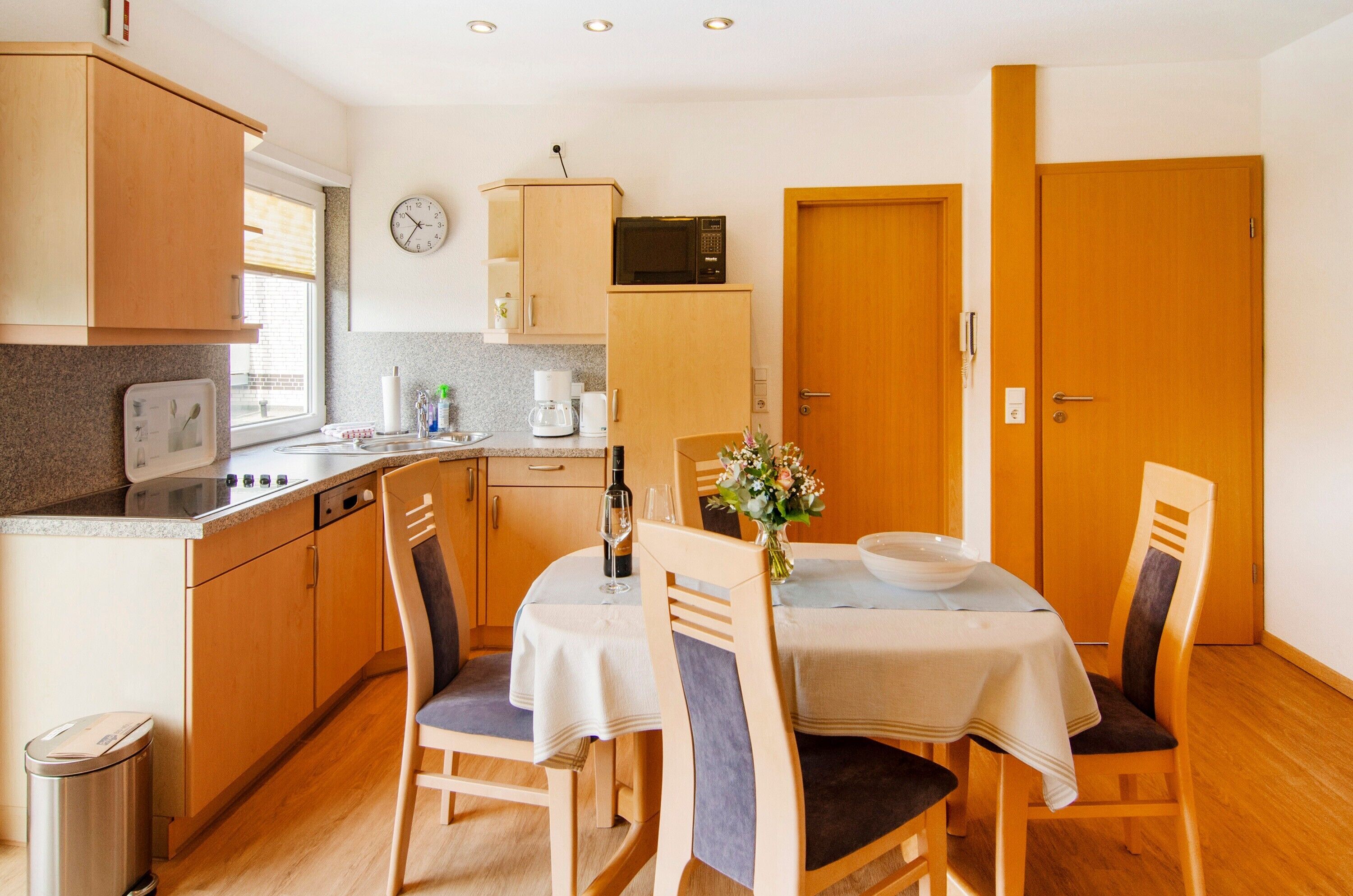 Une cuisine compacte dotée de meubles en bois, d’un four à micro-ondes, d’un évier et d’un coin repas avec une table et des chaises.