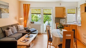 Una sala de estar moderna con sofá, mesa de centro y comedor con sillas y mesa.