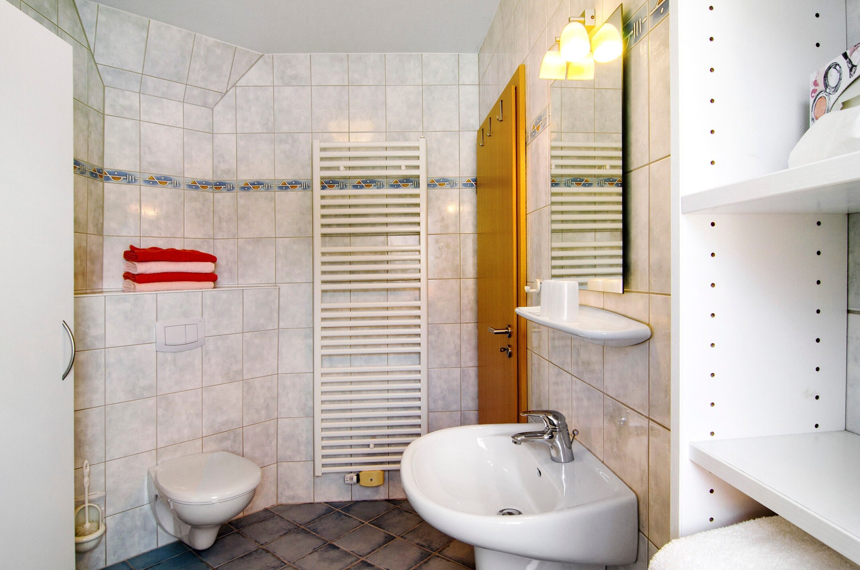 Un baño con inodoro, lavamanos y toallero.