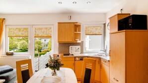 Una cocina compacta con armarios de madera, un microondas y una zona de comedor con una mesa y sillas.