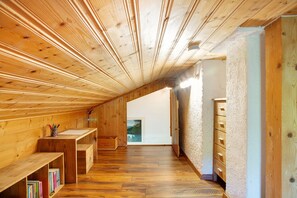 A wooden interior with a sloped ceiling, wooden benches, a desk, and a view through a window. - Holiday Home 'Berghütte Waldhäuser' with Mountain View, Private Terrace and Wi-Fi (Neuschönau)