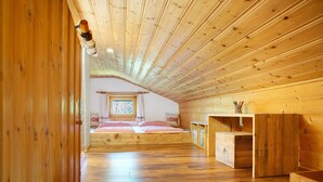 A wooden interior with a loft bedroom, a window with a view, and a wooden desk. - Holiday Home 'Berghütte Waldhäuser' with Mountain View, Private Terrace and Wi-Fi (Neuschönau)