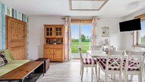 Une pièce comprenant un lit, une armoire en bois, une table à manger avec des chaises et un téléviseur.