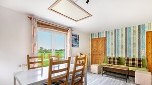 A room with a dining table, chairs, a sofa, a bench, and a view of the outdoors. - Holiday Apartment 'Erika' – Quiet Location with Large Garden near the Baltic Sea & Schlei (Saustrup)