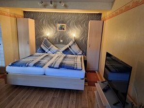 A modern bedroom with a bed, a television, and a small picture on the wall. - Pension Andrea: Apartment 3 with Wi-Fi (Herbstein)