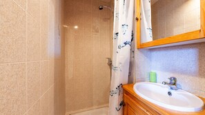 Un bagno con doccia, lavandino e specchio.