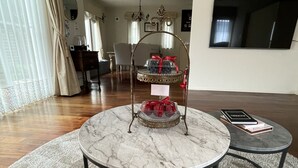 A living room with a round marble coffee table, a small side table, and a decorative stand with a red ribbon. - Maccha House Nagano Zenko-ji (Nagano)