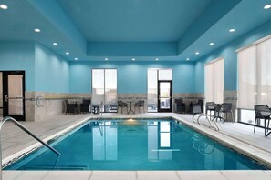 An indoor swimming pool with clear blue water, surrounded by a blue-tiled floor and walls, with seating areas and large windows. - Hampton Inn & Suites Amarillo West (Amarillo)