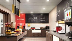 Une cuisine moderne dotée d’un îlot central, d’un panneau rouge en forme de gaufre et d’un coin café.