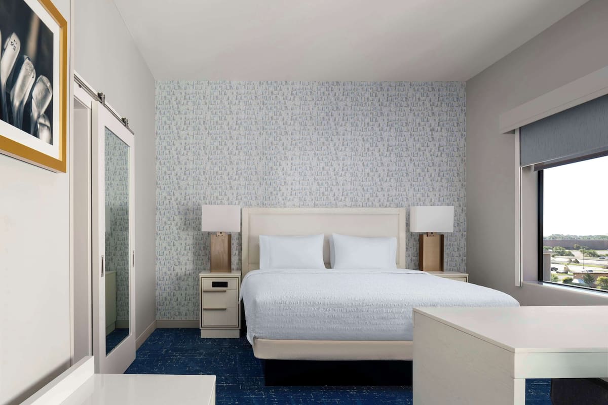 A hotel room with a bed, bedside tables, a desk, and a window with a view.
