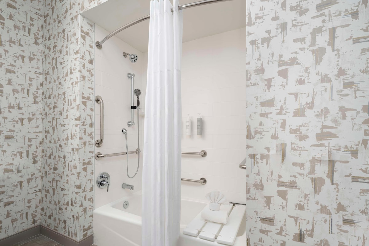 Une salle de bain moderne équipée d’une douche, de barres d’appui et d’une baignoire.