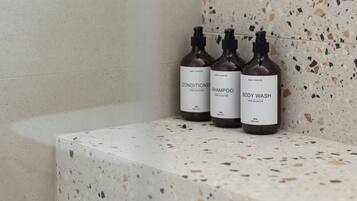 Three bottles of body wash on a speckled countertop in a bathroom.