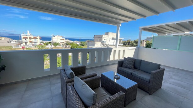 A covered outdoor seating area with wicker furniture and a view of the sea. - Kallisti Stay (Spata-Artemida)