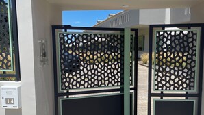 A modern building entrance with a decorative metal gate, a mailbox, and a paved driveway. - Kallisti Stay (Spata-Artemida)