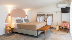 A neatly arranged bedroom with a bed, bedside table, bench, and a wardrobe with hanging clothes. - Kallisti Stay (Spata-Artemida)
