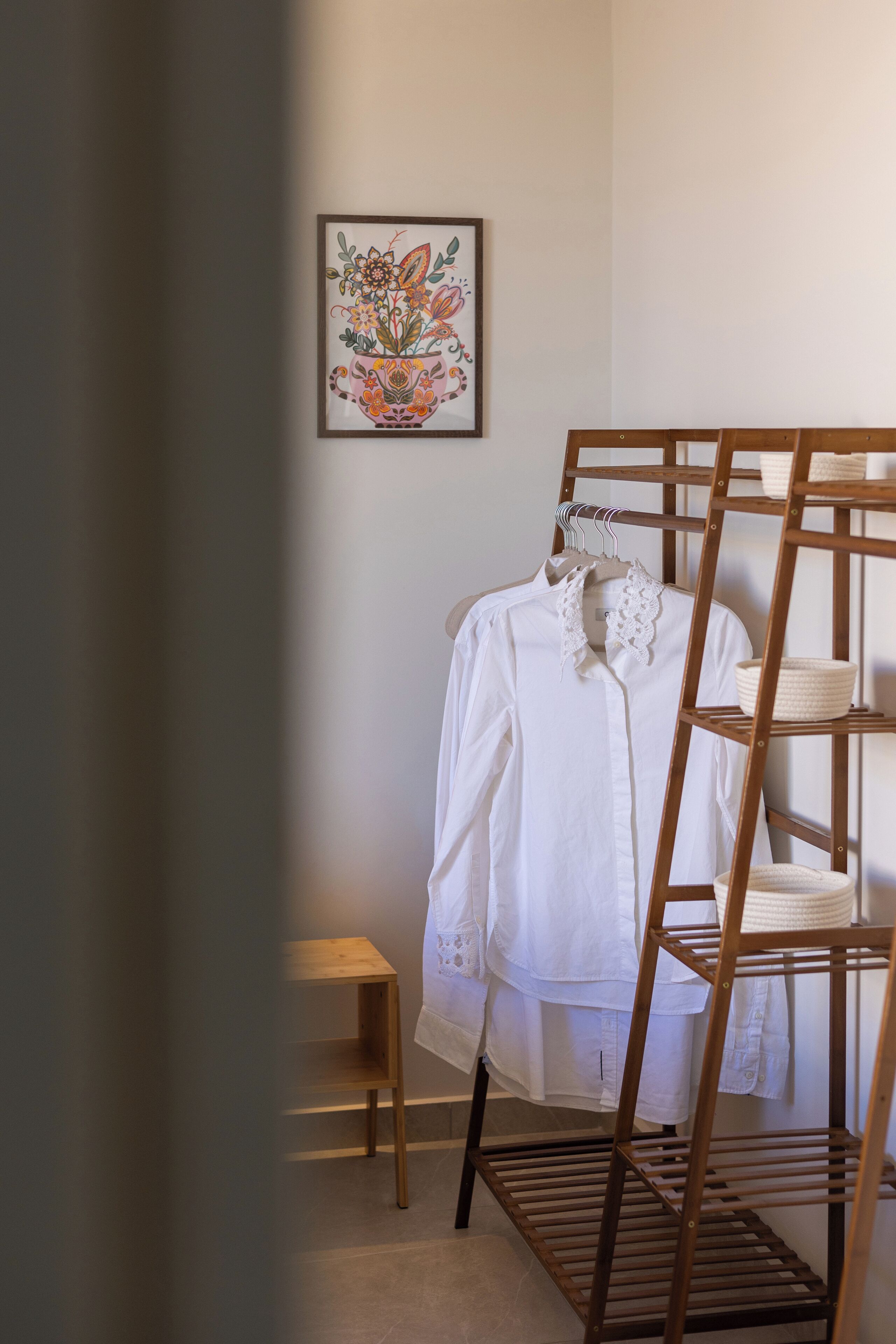 A bedroom with a wooden bunk bed, a small wooden stool, and a framed floral artwork on the wall.