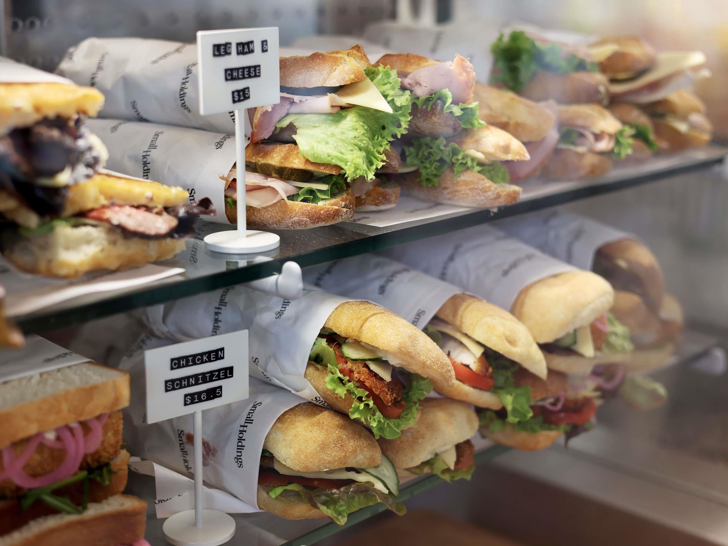 A display case with sandwiches labeled 'LEG HAM & CHEESE' and 'CHICKEN SNITZEL.'