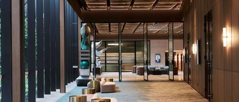 A modern hotel lobby with a long corridor, seating areas, and a reception desk.