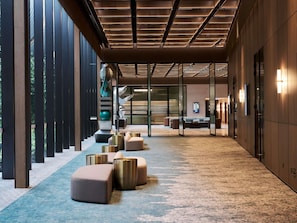 A modern hotel lobby with a long corridor, seating areas, and a reception desk.