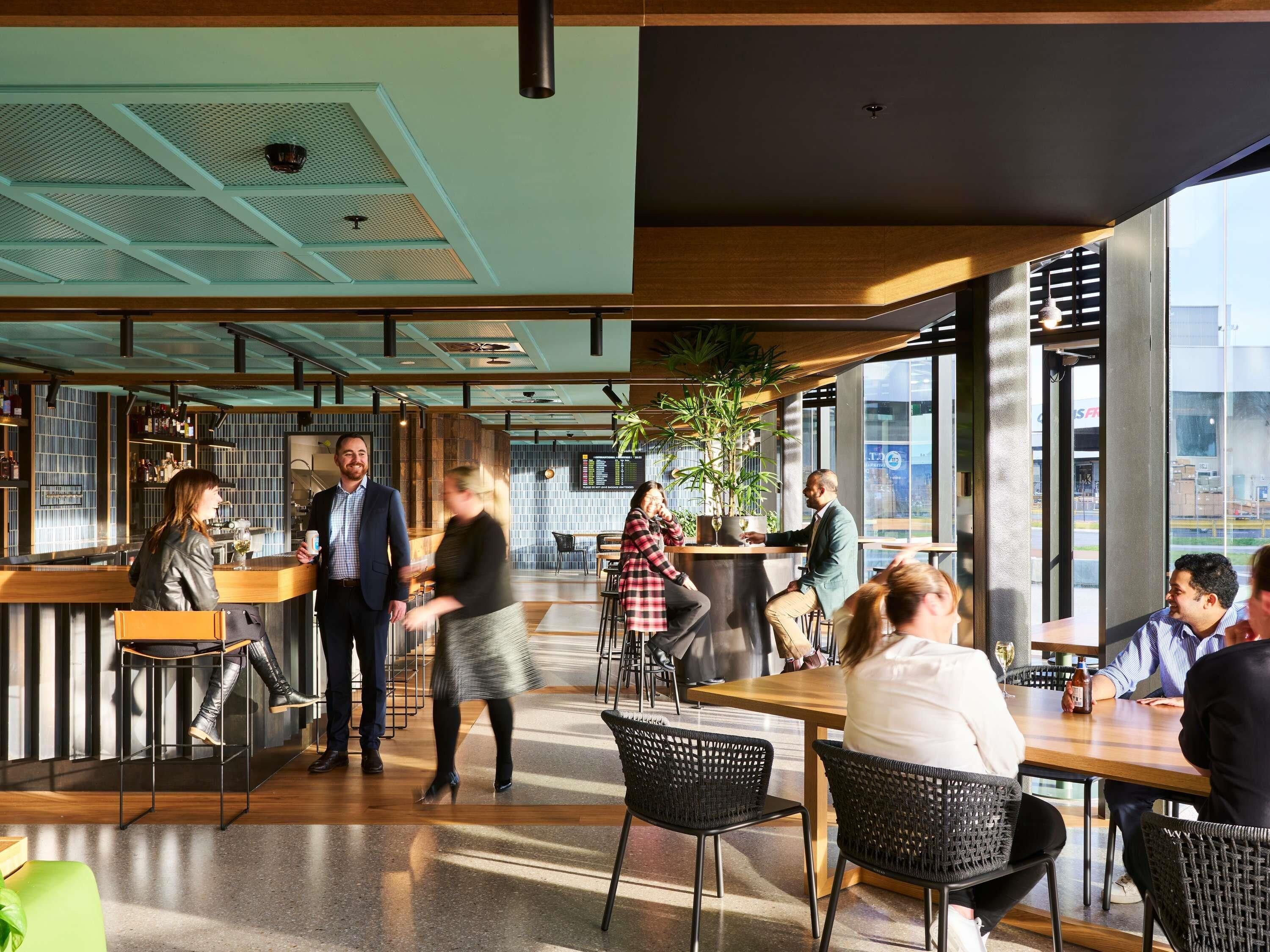 A modern interior with a bar area, seating, and large windows.