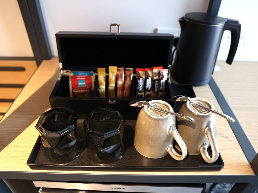 Una bandeja con cafetera, taza, termo y varios pods de café sobre una mesa.