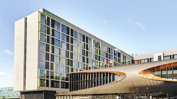Een modern gebouw met een gebogen glazen gevel en een bord waarop staat: 'Dit is ons gebouw'.