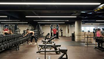 Uma academia com diversos equipamentos de exercícios, incluindo halteres, bancos e máquinas de musculação.