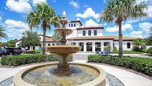A fountain in a landscaped area with palm trees and a building in the background. - Premium 5-Bed Townhome, Themed, Perfect Location (Kissimmee)