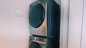 A compact laundry room with two stacked front-loading washing machines, a fire extinguisher, and a power outlet on the wall. - La mejor vista de Quito Piso 28 IQON (Quito)