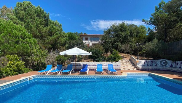 A swimming pool with blue lounge chairs and a white umbrella.
