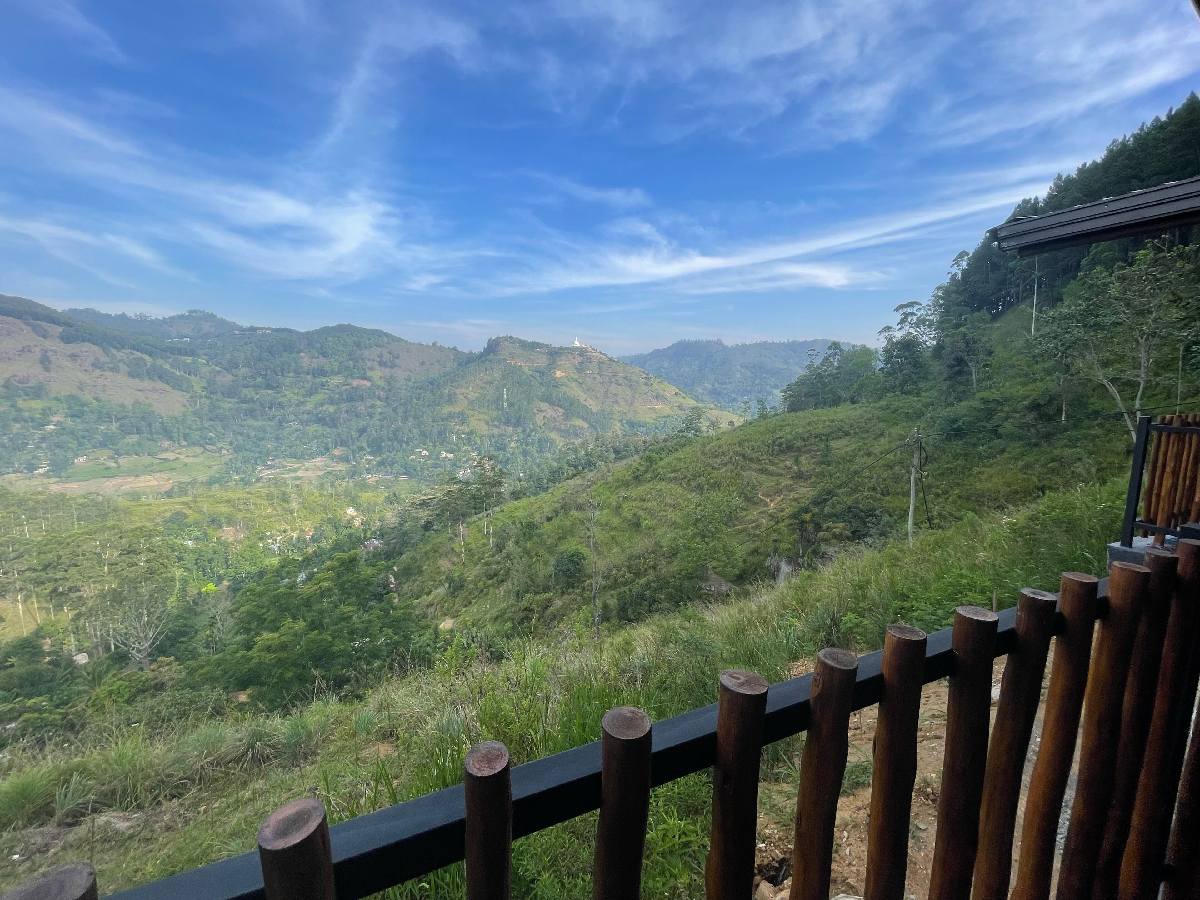 A scenic view from a wooden deck overlooking lush green hills and a valley.
