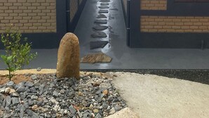 A pathway leading to a building with brick walls and a metal roof.