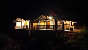 A modern house with a balcony, a staircase, and a covered porch area.