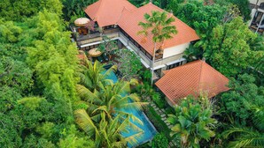 Un resort tropical con varias construcciones, abundante vegetación y una piscina.