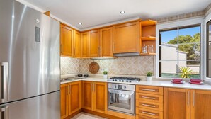 A kitchen with wooden cabinets, a stainless steel refrigerator, an oven, and a window with a view of greenery. - A Midsummer Stay`s Dream (Son Parc)