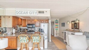 Una cocina moderna con armarios de madera, una isla central y dos taburetes de mimbre.